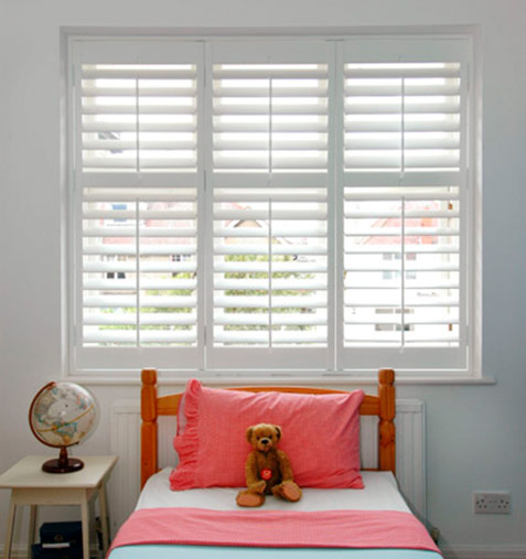 childrens room with teddy bear, globe and white shutters